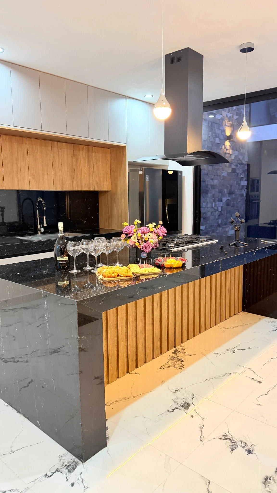 Cocina principal de CASA GH con madera, piedra e iluminación lineal